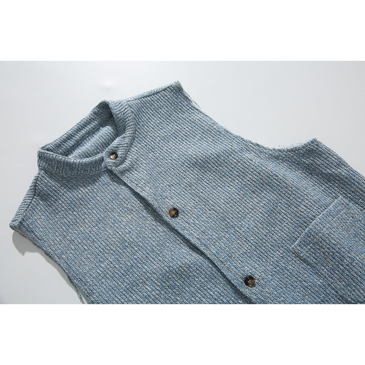 Close view of a blue-gray textured sleeveless vest front with a stand collar and dark buttons.