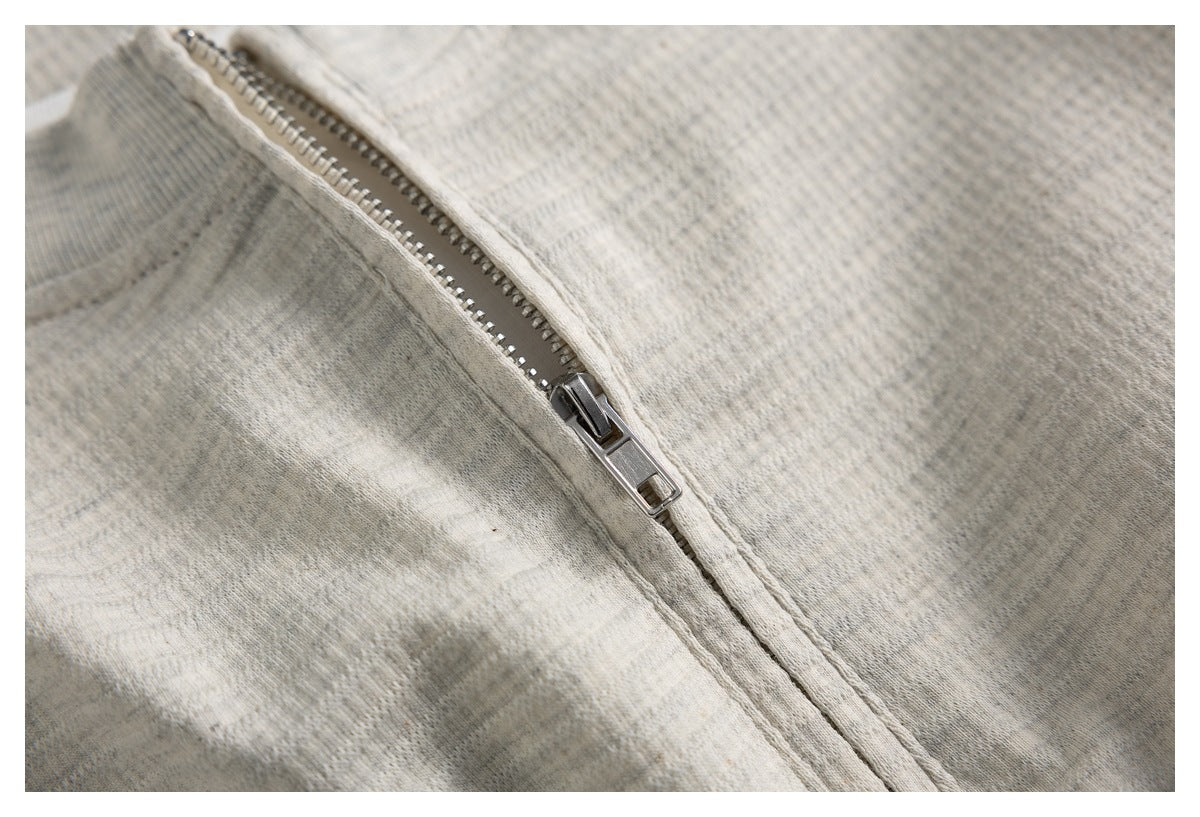 Close-up of the silver zipper and textured light gray knit fabric on the top.