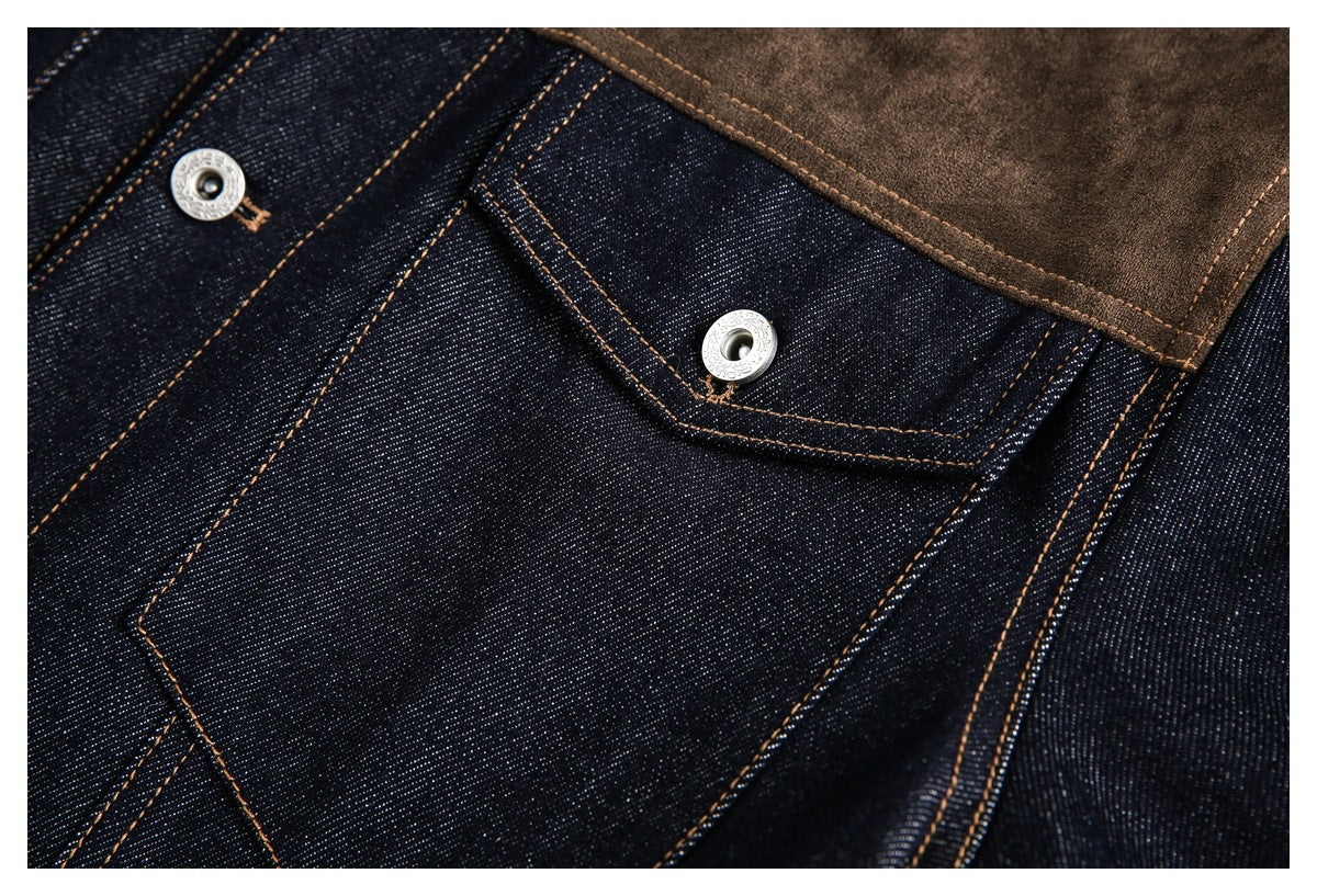 Close-up of a dark indigo denim jacket pocket with silver snap buttons, tan stitching, and a brown shoulder panel.