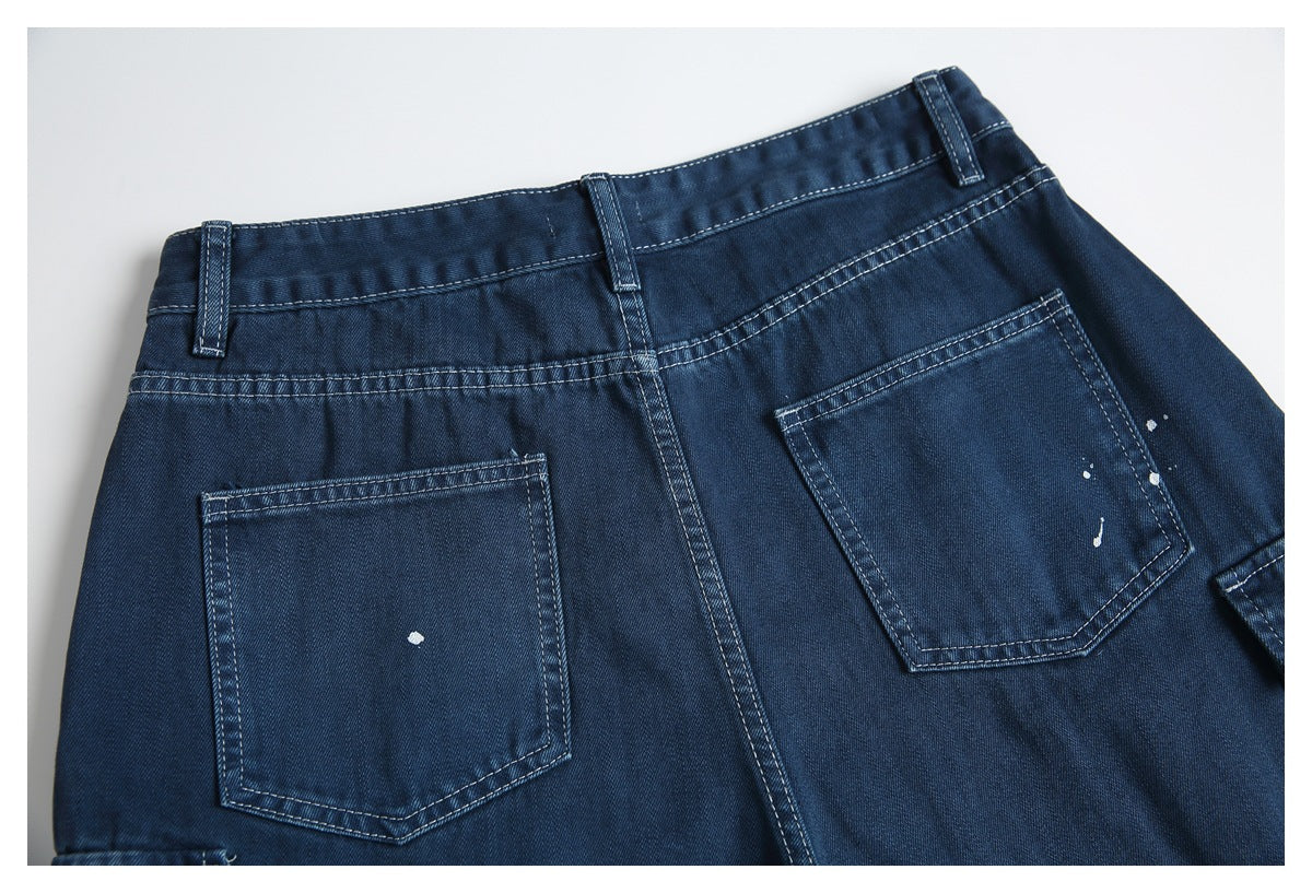 Back view of dark blue jeans with two patch pockets, belt loops and scattered white paint-like flecks.