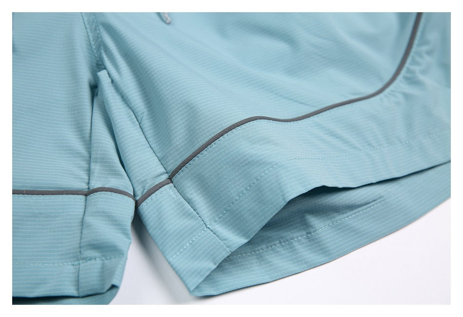 Close-up of aqua shorts showing the curved gray piping, seam and folded hem.