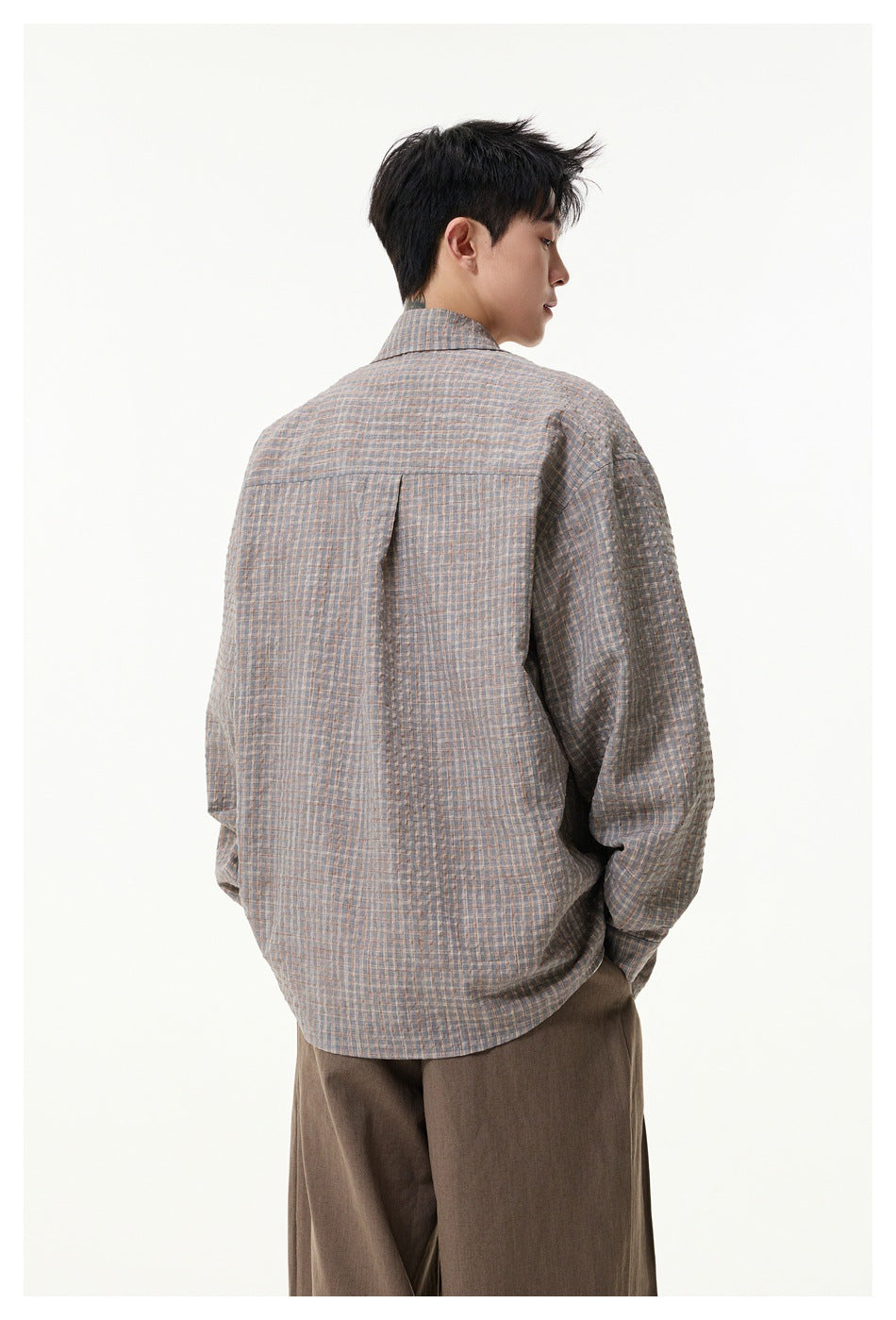 Back view of a model wearing a loose gray blue-and-tan checked shirt with a center back pleat.