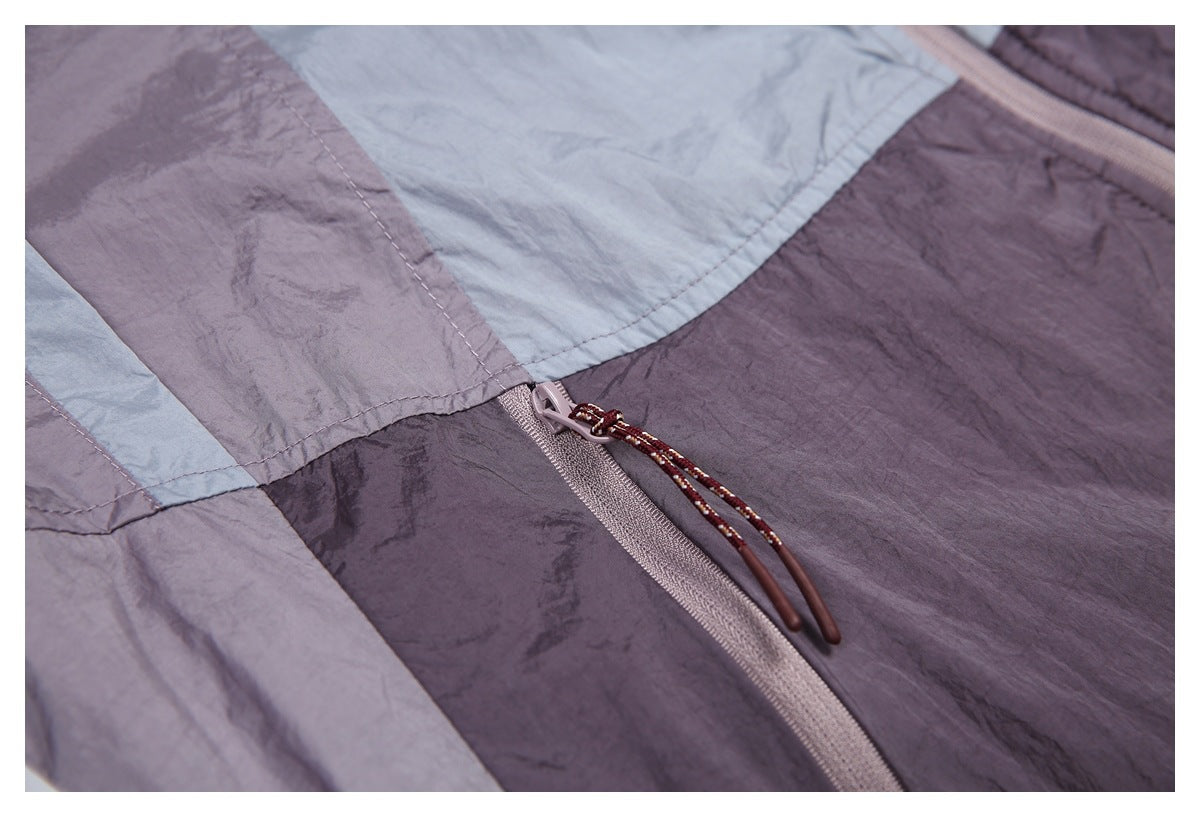 Close-up of a purple-gray color-block jacket with a pale zipper and long corded pull.