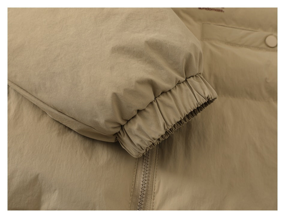 Close-up of a beige jacket's gathered elastic cuff beside the front zipper.