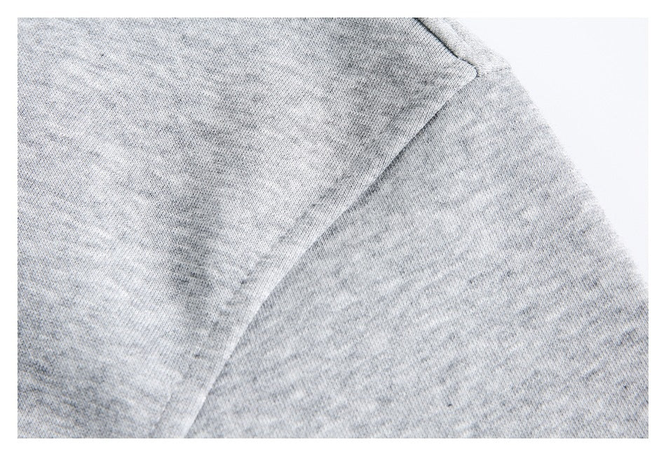 Close-up of a seam on the gray heathered fabric of a jacket.