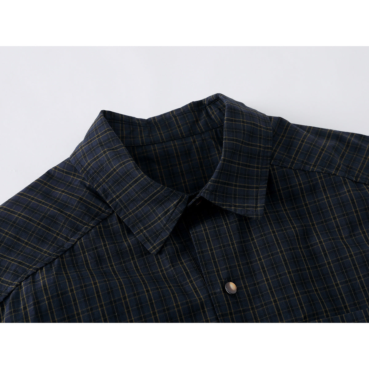 Close-up of a dark navy plaid shirt showing its pointed collar, front placket and button.