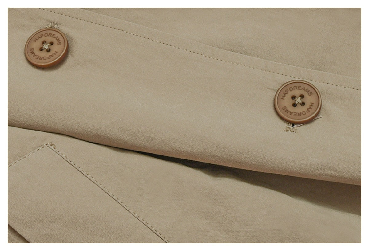Close-up of two brown buttons embossed with English lettering on a beige coat.