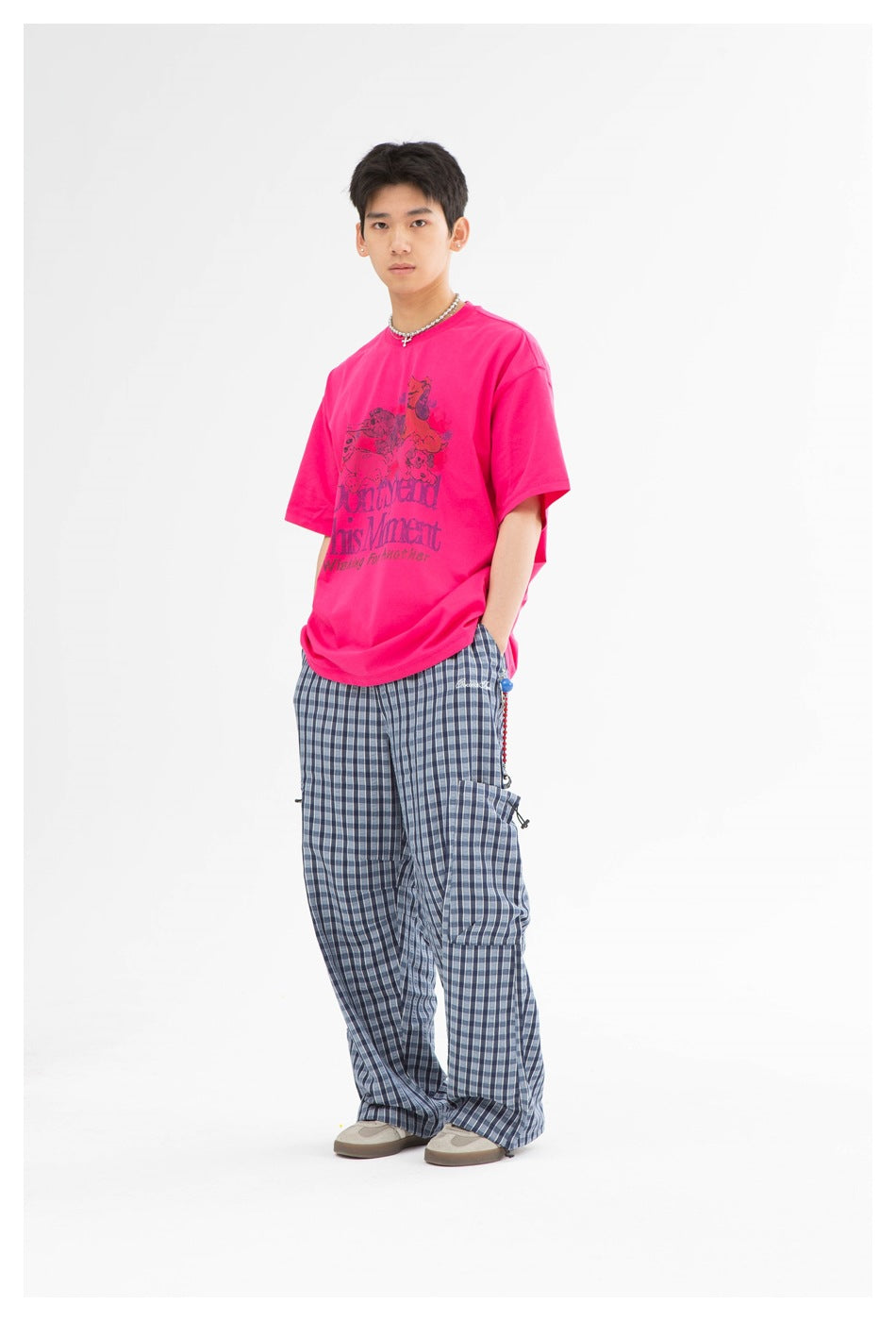 Full-length front view of a model wearing a hot-pink animal graphic T-shirt and blue plaid trousers.