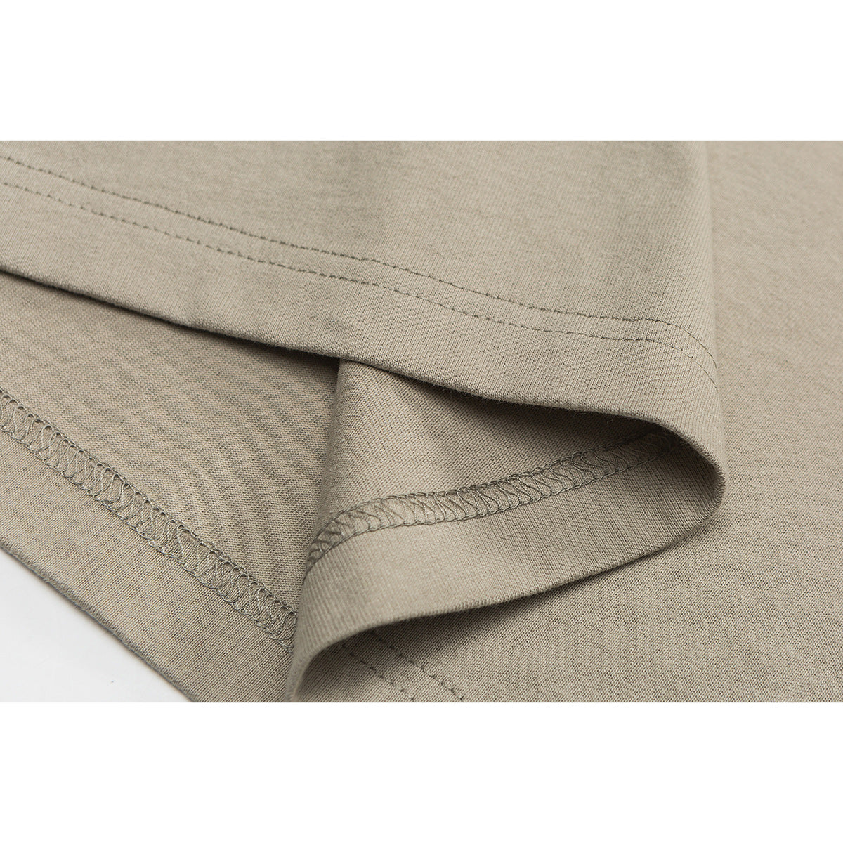 Close-up of the beige shirt's folded hem, showing its double stitching and overlocked inside seam.