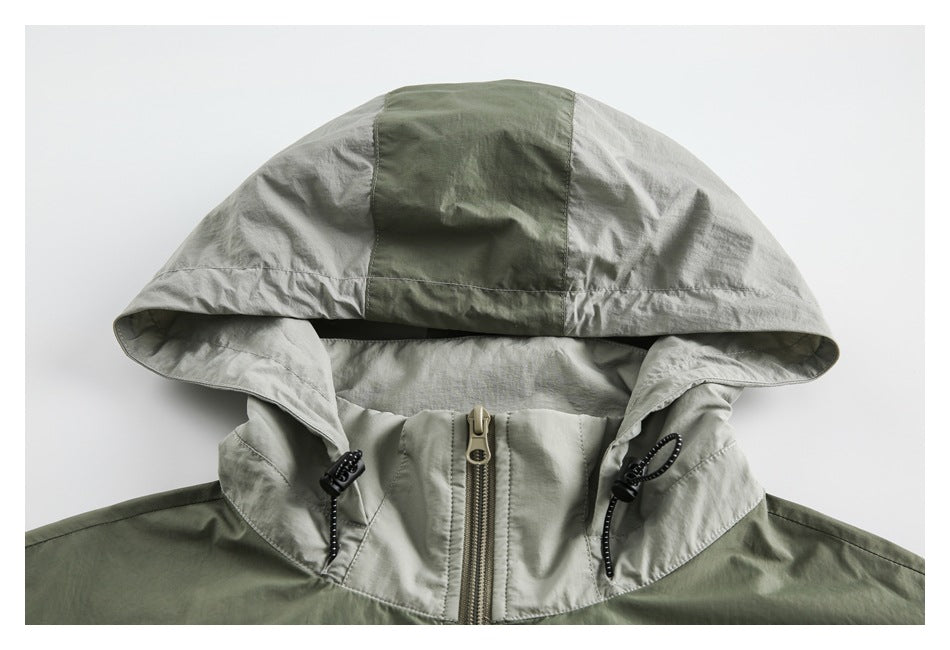 Front close-up of a sage green color-block jacket with a large hood, drawcords and center zipper.