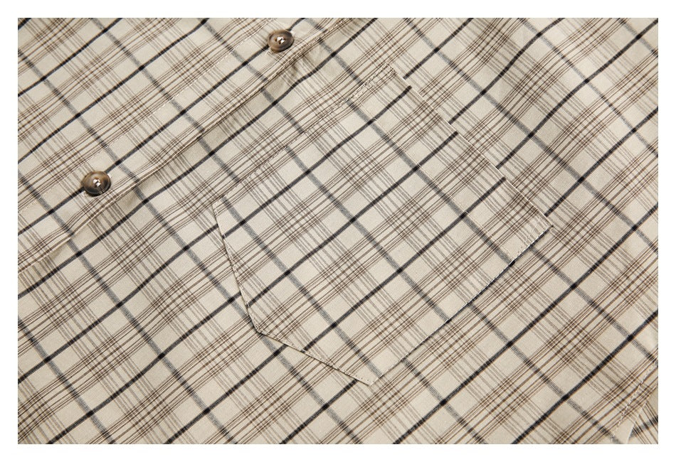 Close-up of a cream plaid shirt's chest pocket and brown front buttons.