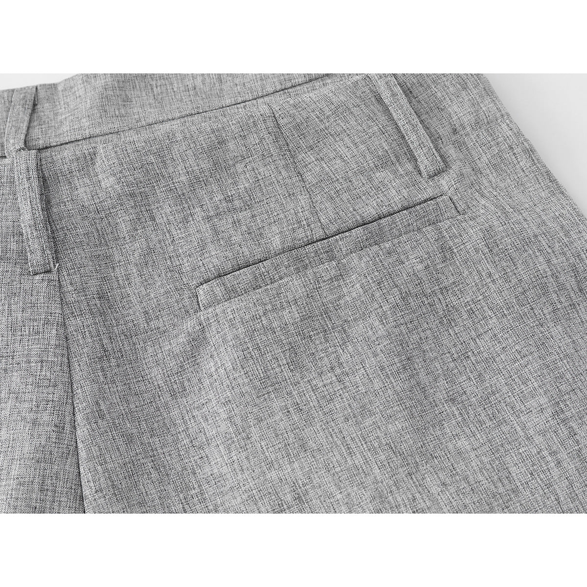 Close-up of gray trousers showing a belt loop and welt pocket on the back.