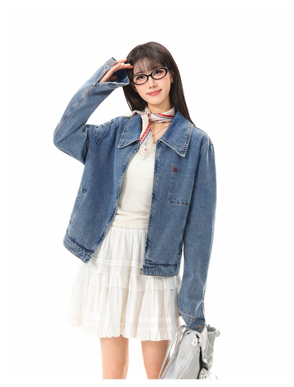 Model posing in a blue denim jacket with oversized collar and chest pocket over a white ruffled dress.