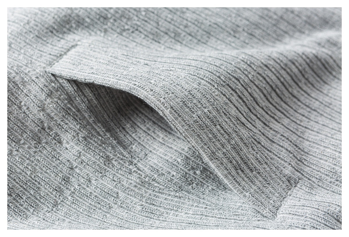 Close-up of a curved opening and rib-knit edge on the light gray sweater.