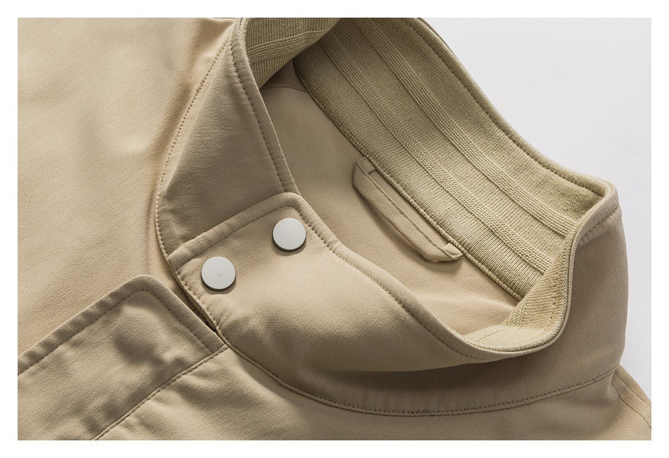 Close-up of a tan jacket's ribbed collar, inner snap-button tab, and stitching.