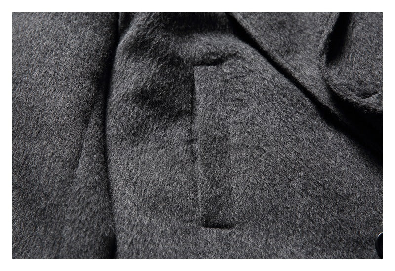 Close-up of a rectangular pocket on the charcoal gray coat front.