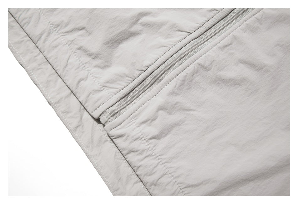 Close-up of a pale gray garment showing a diagonal zipper and stitched seams.