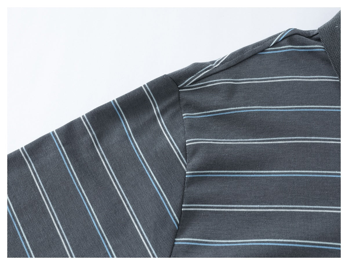 Close-up of a charcoal gray shirt shoulder and sleeve with thin white and light blue stripes.