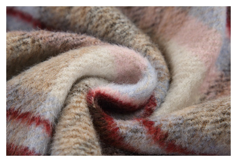 Close-up of the soft, fuzzy plaid fabric gathered into folds, with beige, gray, pink, blue, and red tones.