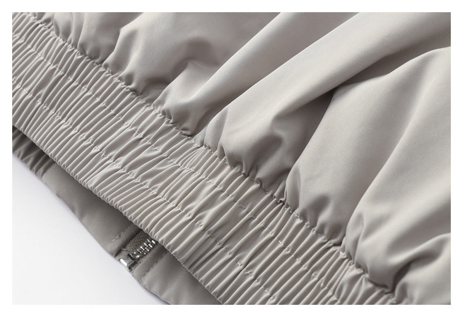 Close-up of a gathered elastic edge on a light gray garment, with a small zipper visible beneath it.