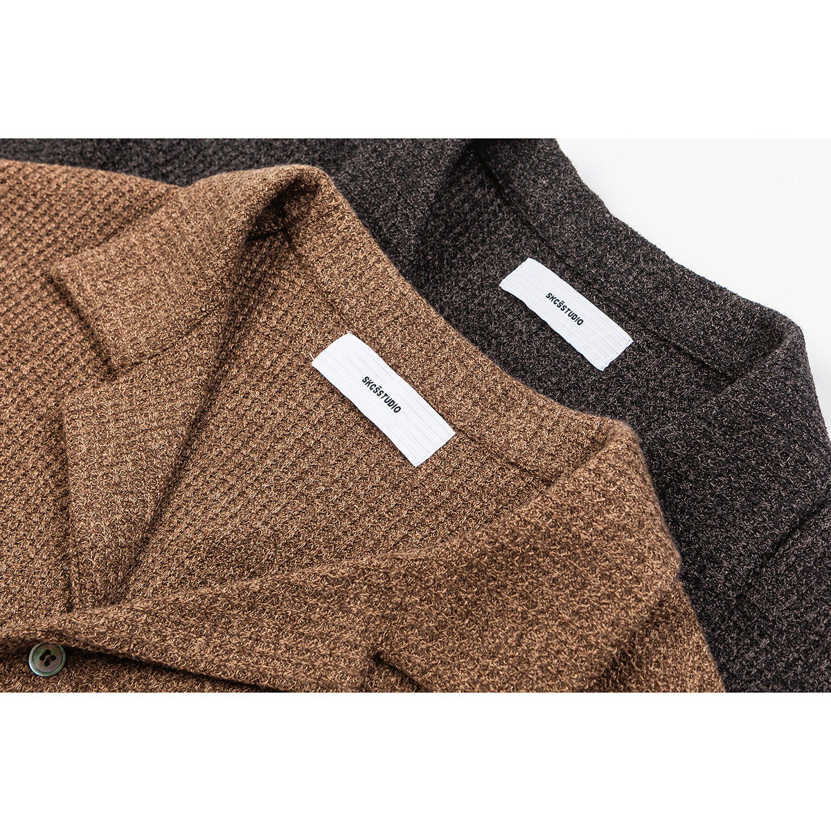 Close-up of brown and charcoal knit shirt collars with white neck labels and a button.