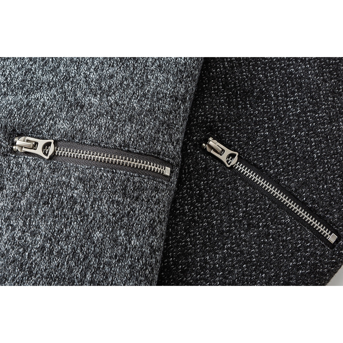 Close-up of metal zippers on gray and black marled fabric.
