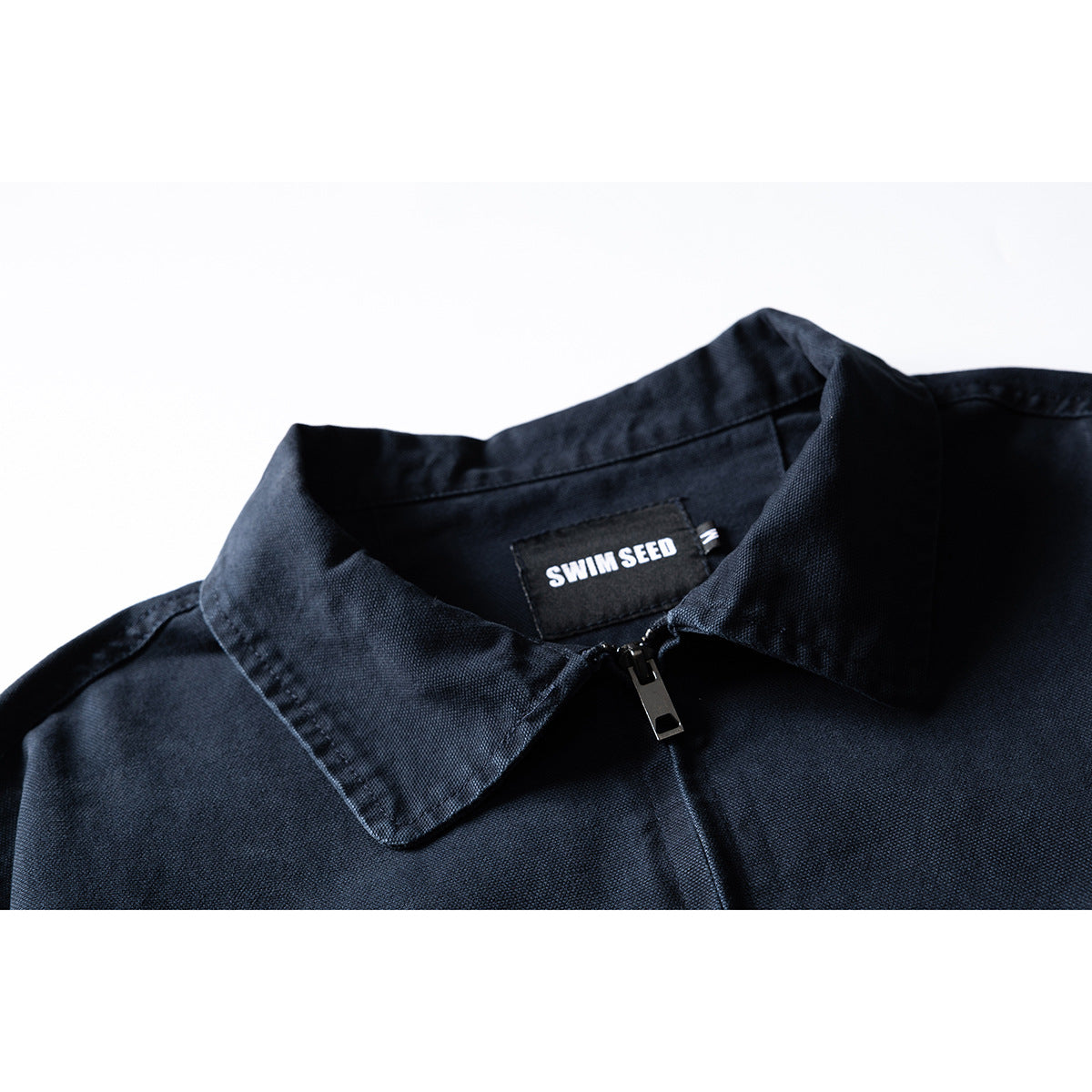 Close-up of a dark navy jacket collar, front zipper and SWIM SEED neck label.