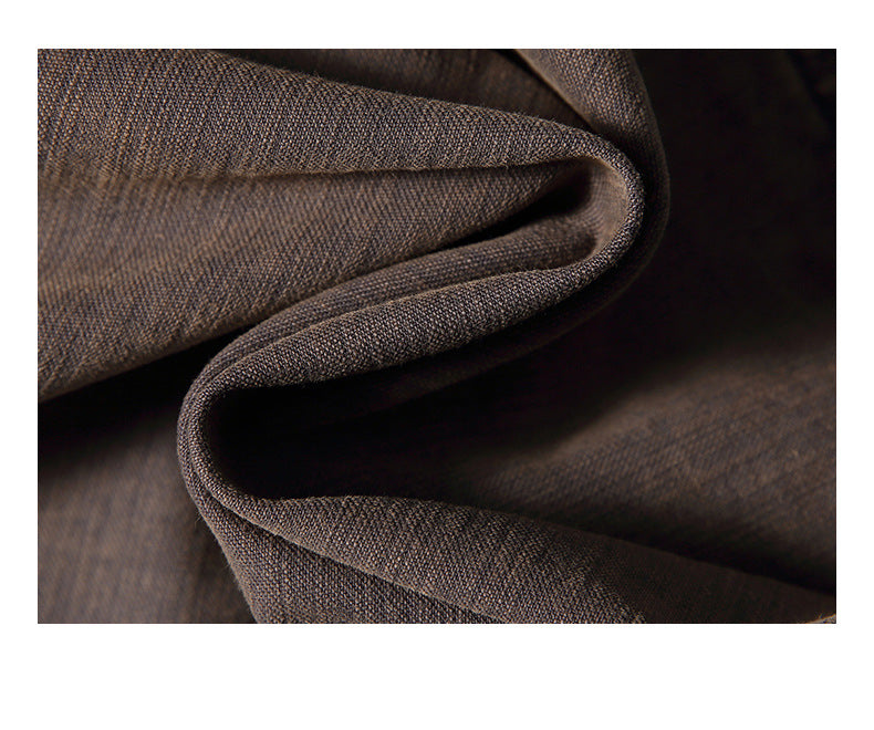 Close-up of dark brown fabric arranged in soft folds, showing its fine texture.