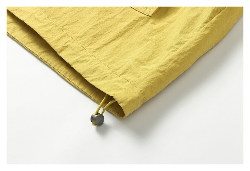 Close-up of a mustard-yellow jacket hem with an adjustable drawcord and toggle.