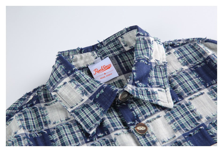 Close-up of the shirt's frayed navy and white plaid fabric, collar, buttons, and sewn-in neck label.