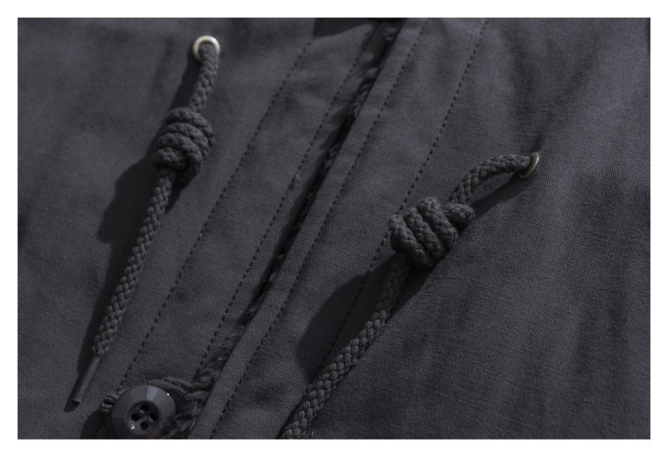 Close-up of a charcoal jacket front with braided toggle cords, metal eyelets, and a black button.