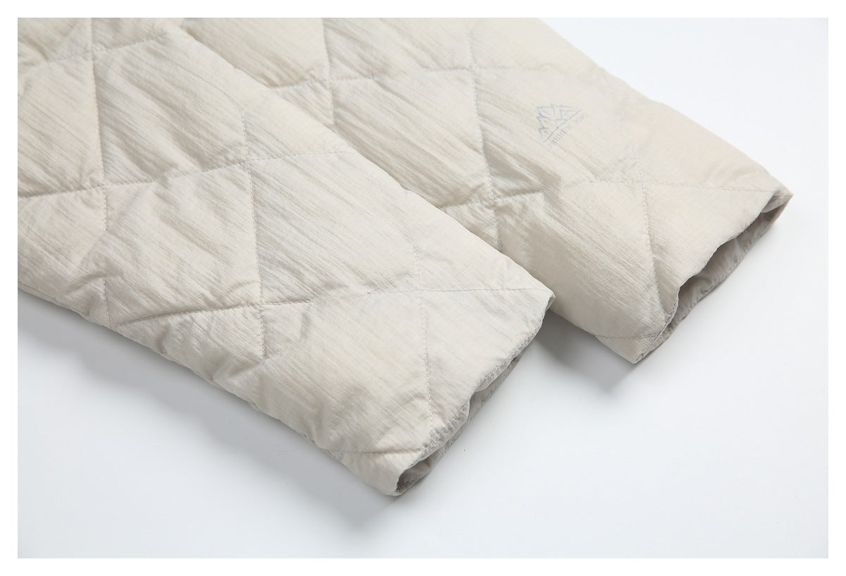 Close-up of cream quilted jacket panels and a stitched edge, with a faint blue mark on the fabric.