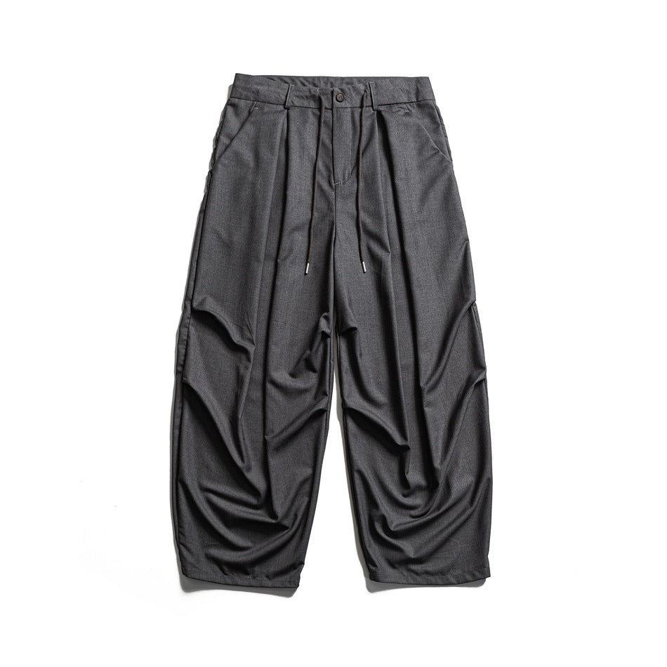 Gray wide-leg pleated trousers with drawstring waist and button front, flat lay front view