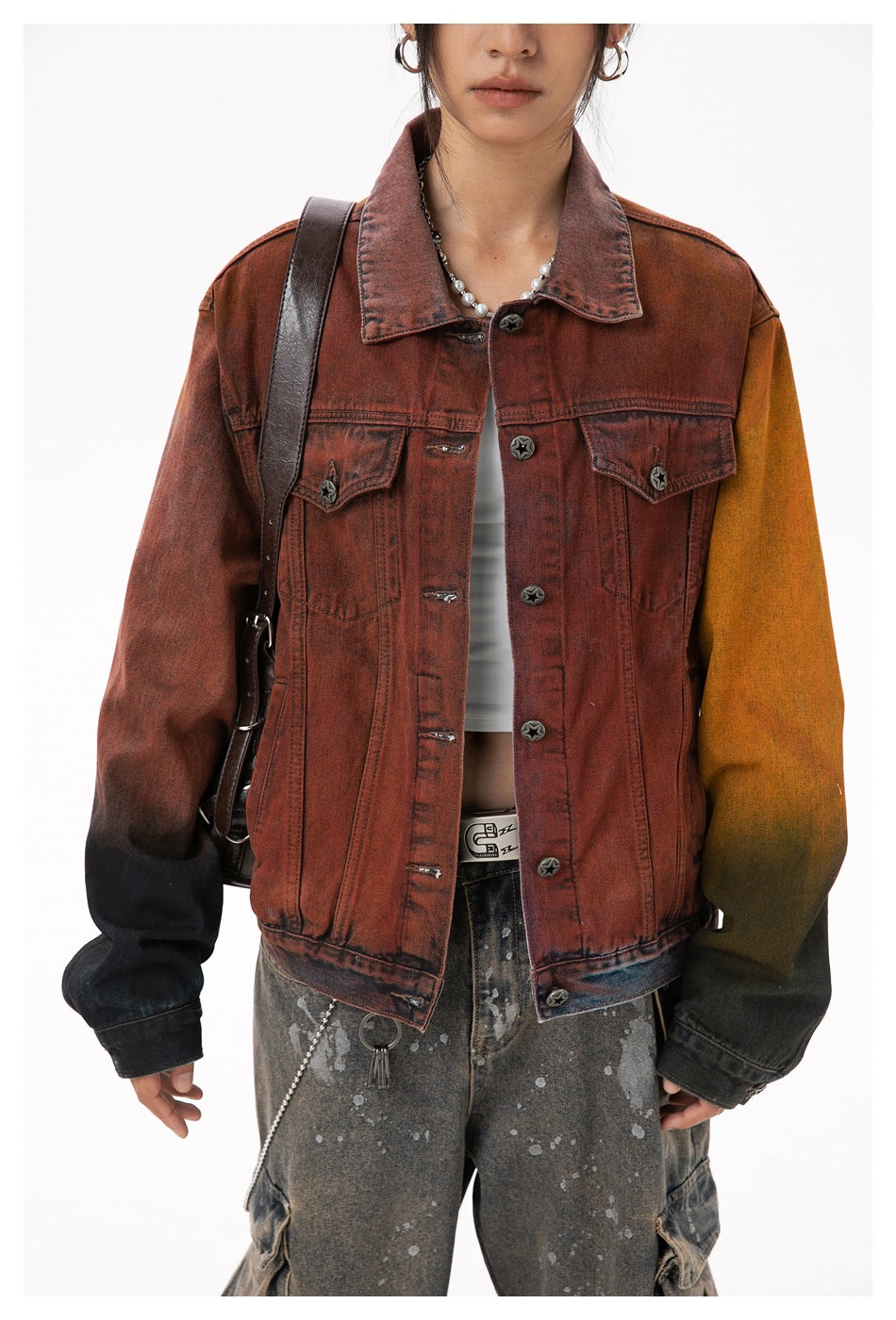 Close view of a model wearing a rust-red denim jacket with contrasting mustard and black sleeves and star-shaped buttons.
