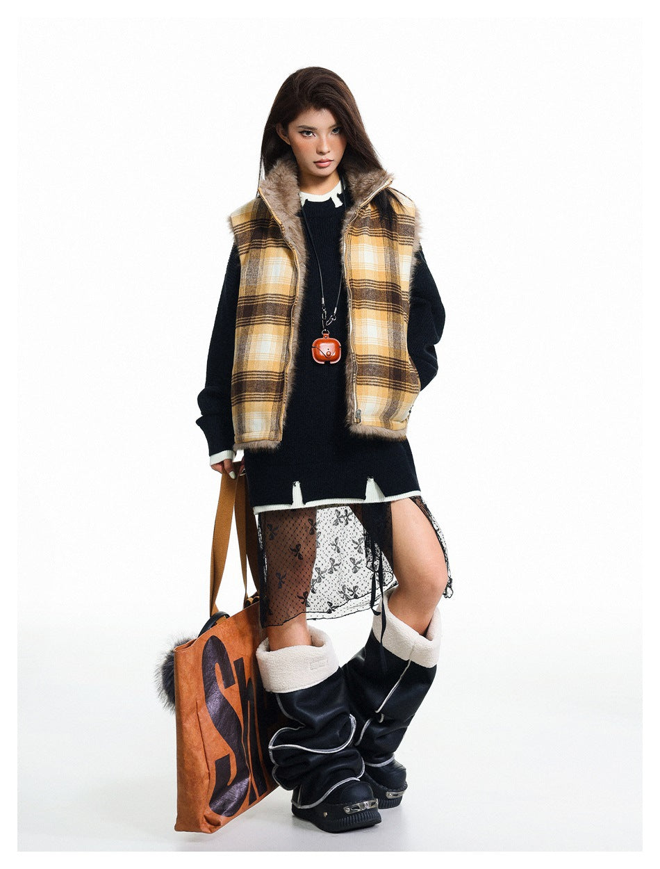 Model in a yellow plaid fur-trimmed vest, black sweater, sheer patterned skirt, and tall black boots, holding a tote.