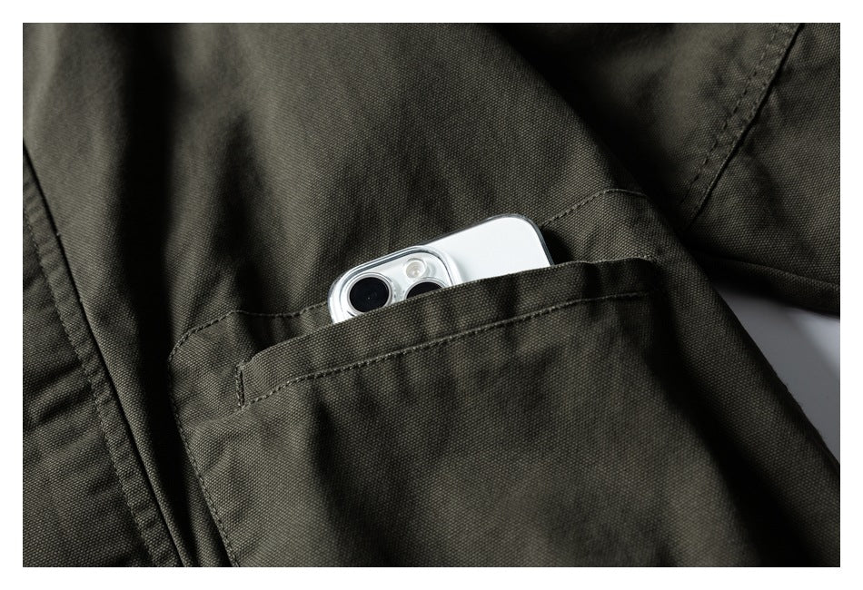 Close-up of a dark olive jacket chest pocket holding a white smartphone.
