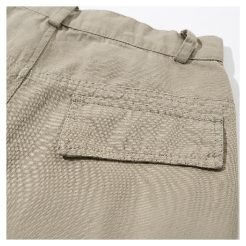 Close-up of the back of beige trousers, showing a rectangular patch pocket and belt loops.