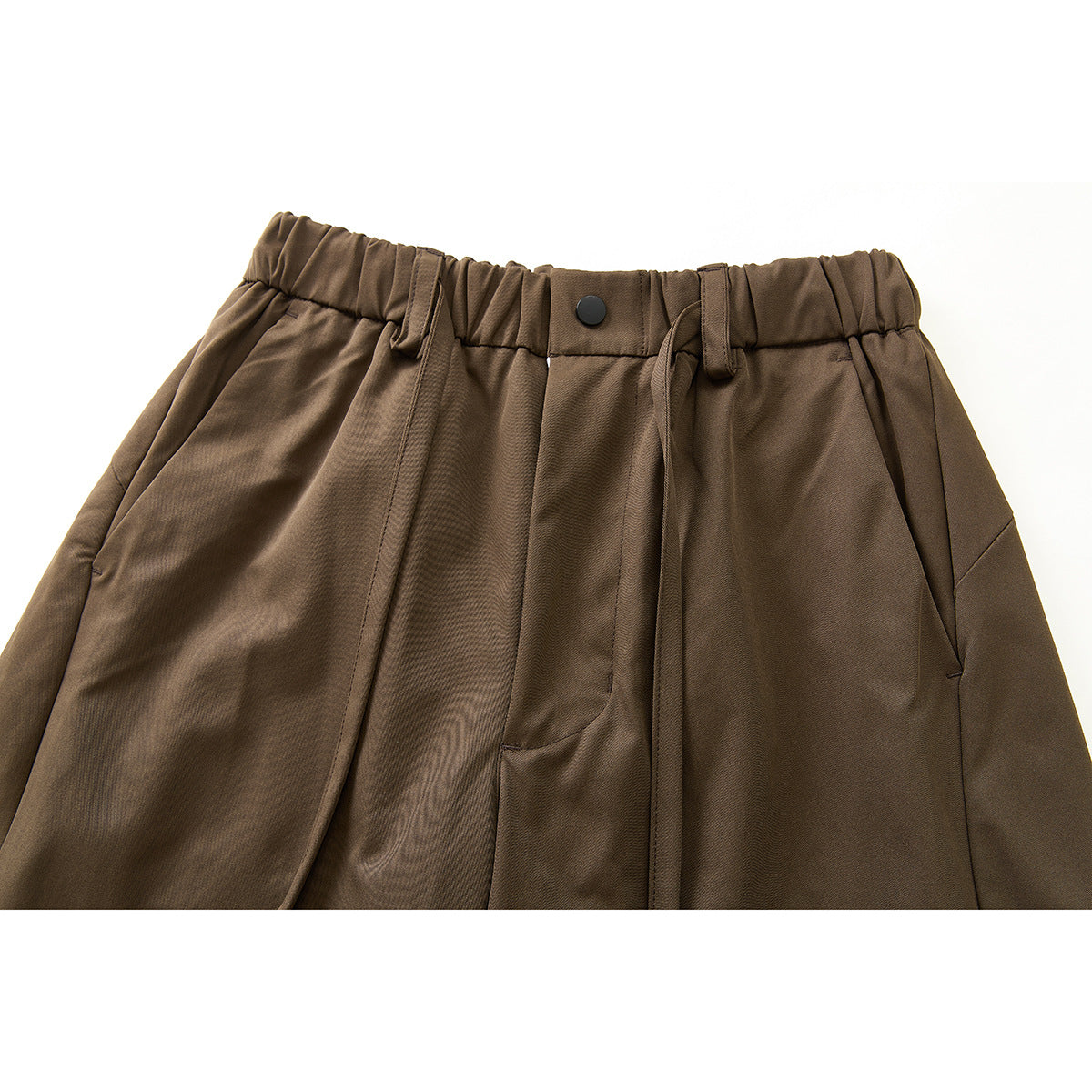Close-up of brown pants showing an elastic waist, button, drawstring, belt loops, and angled pockets.