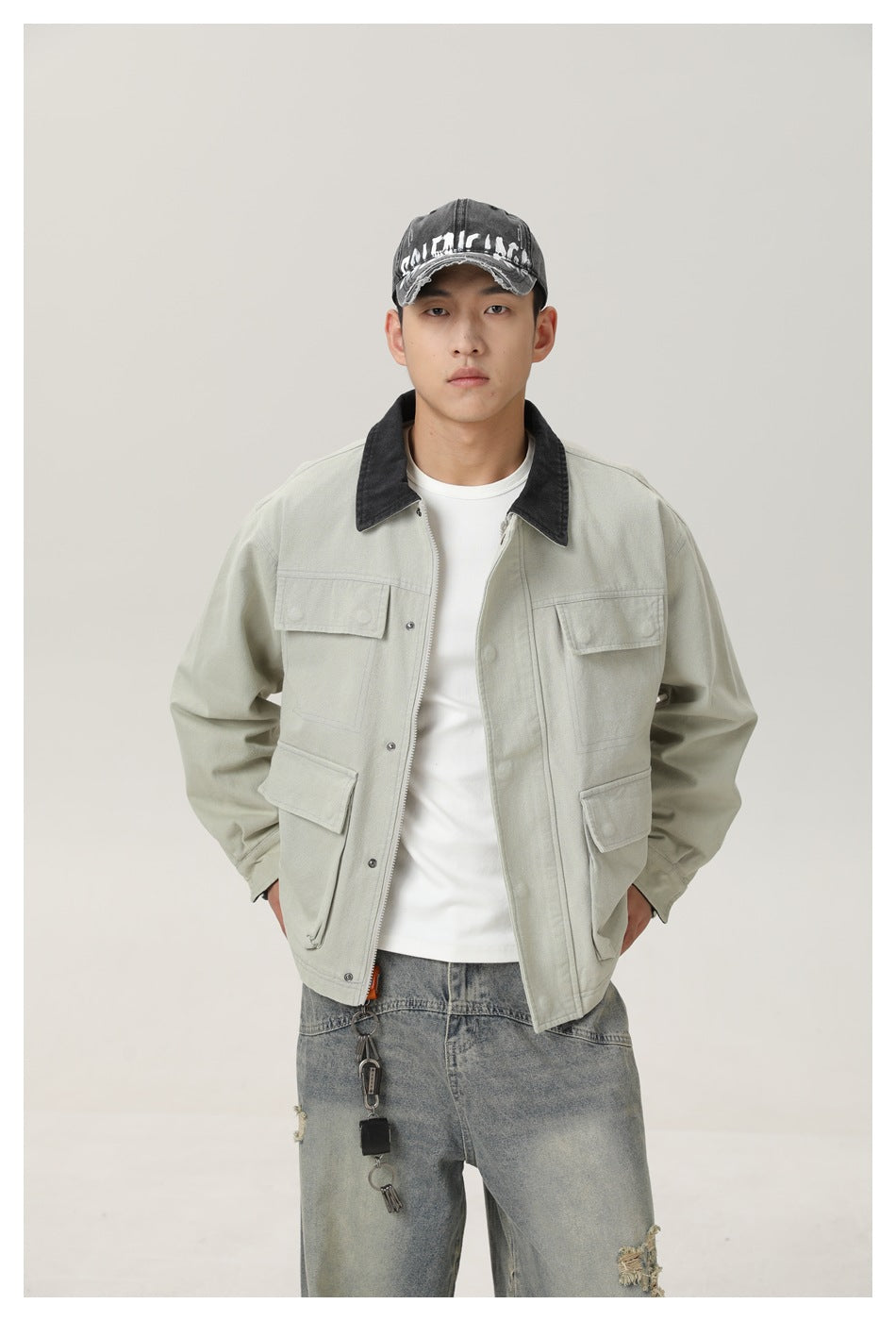 Front view of a model wearing a pale gray-green utility jacket with a dark collar and four flap pockets.