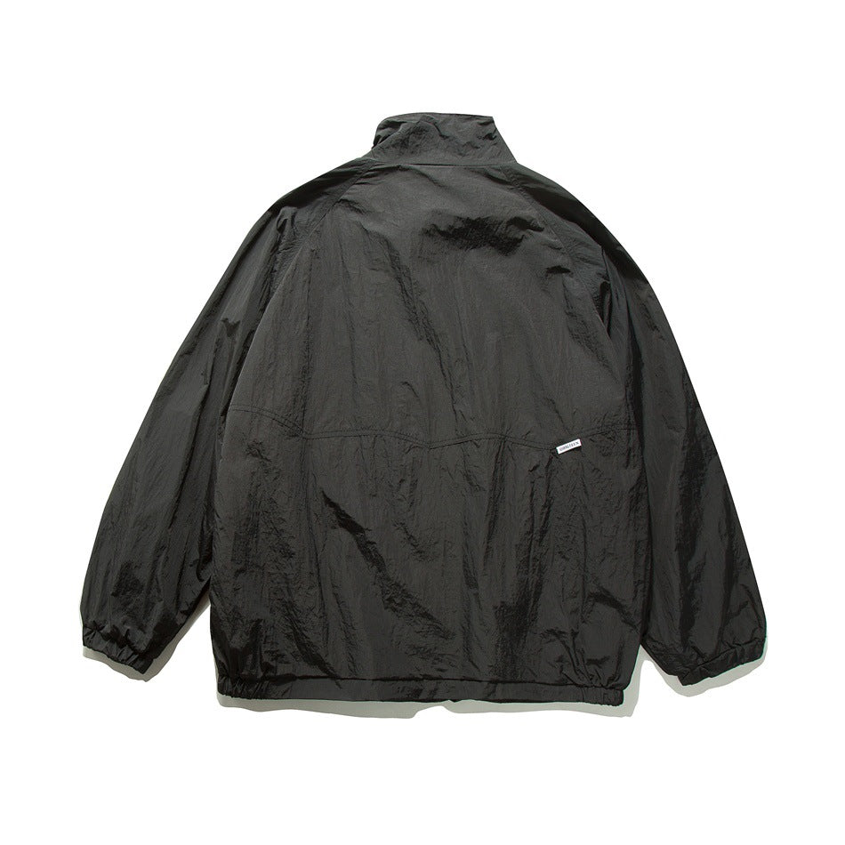 Black jacket back view showing stand collar, back yoke seam, raglan sleeves and elastic cuffs and hem