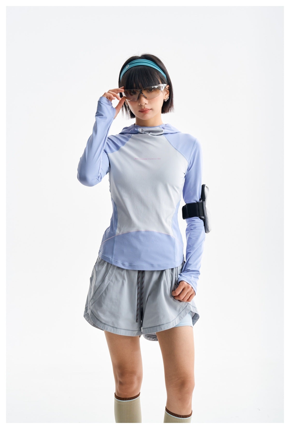 Closer view of a model wearing a light blue and pale gray hooded top with gray shorts.