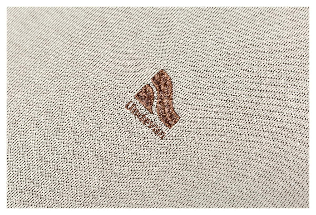Brown embroidered emblem on cream ribbed fabric.