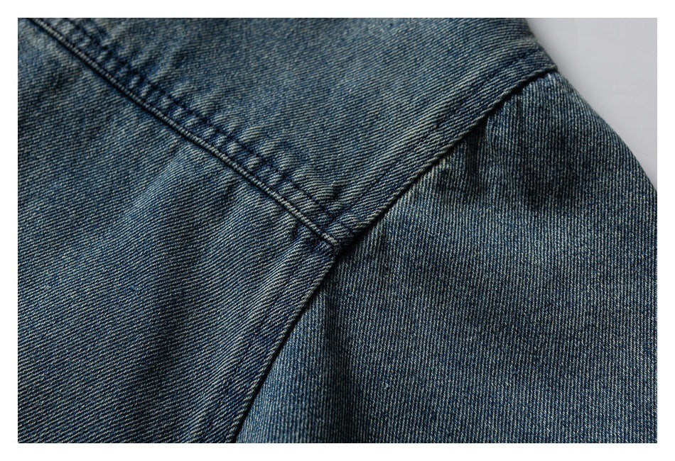 Close-up of blue denim showing intersecting stitched seams and a folded edge.