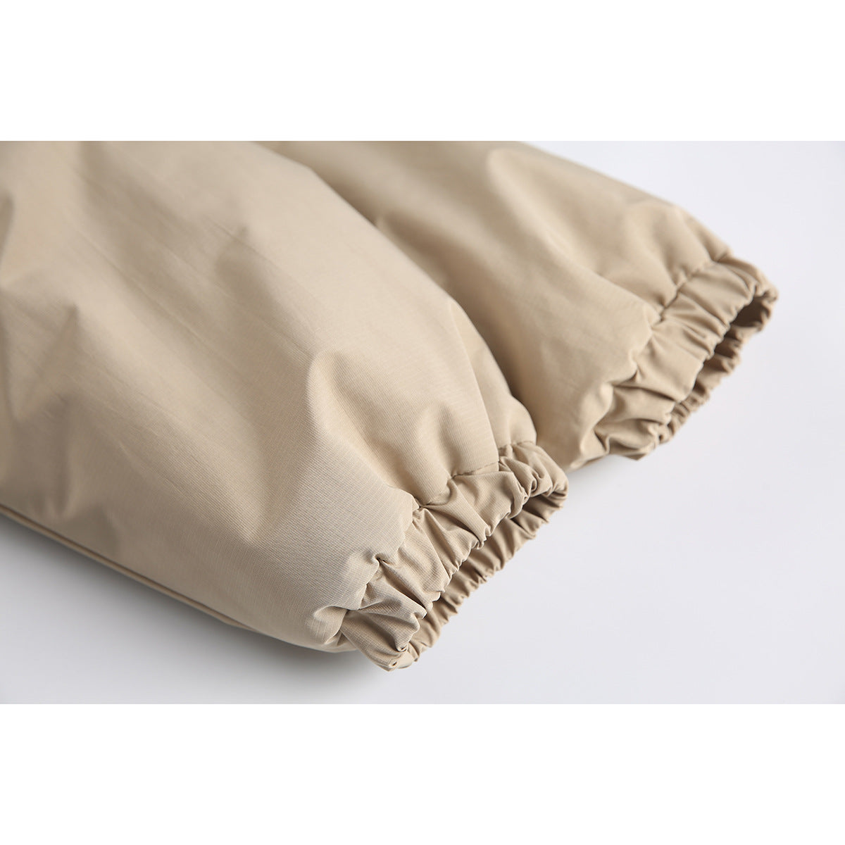 Close-up of the beige jacket sleeve ends with gathered elastic cuffs.