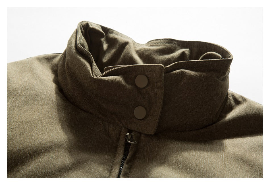 Close-up of an olive-brown jacket's high collar, snap buttons, and front zipper.