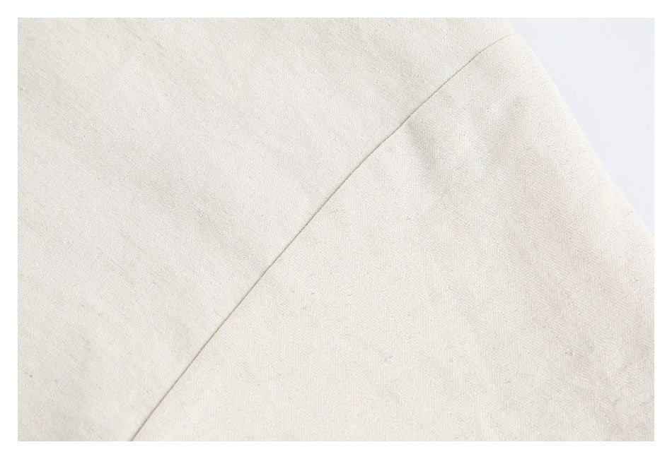Close-up of a curved seam on off-white textured garment fabric.
