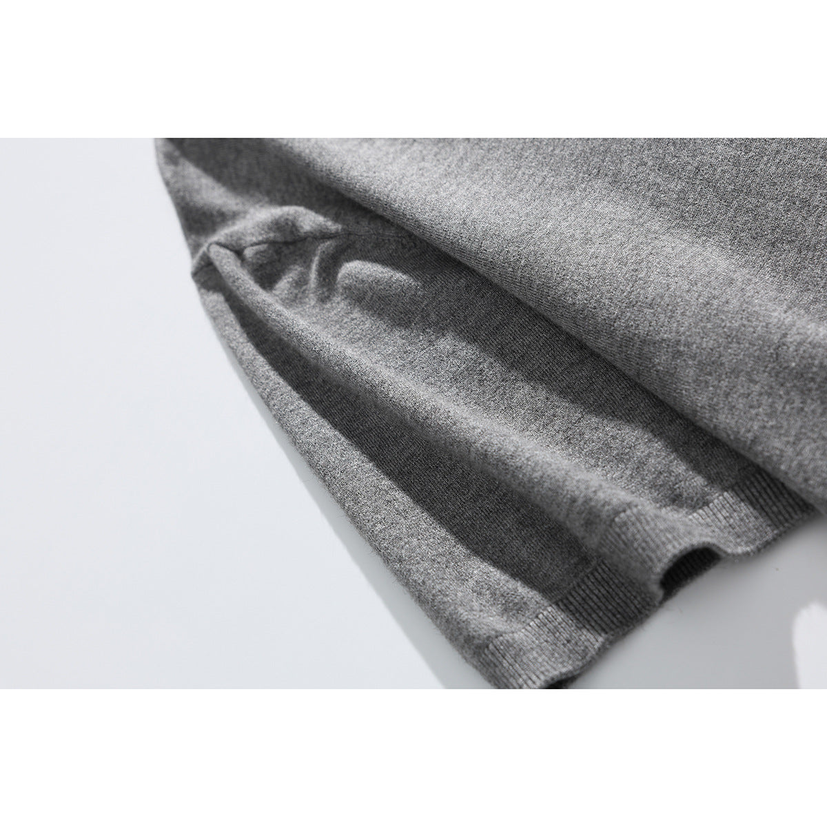 Close-up of the gray knit sweater's folded fabric and ribbed sleeve cuff.