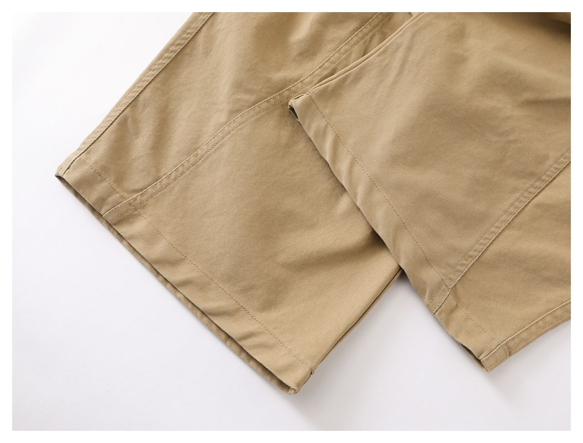 Close-up of tan garment hems and overlapping stitched panels on a white background.
