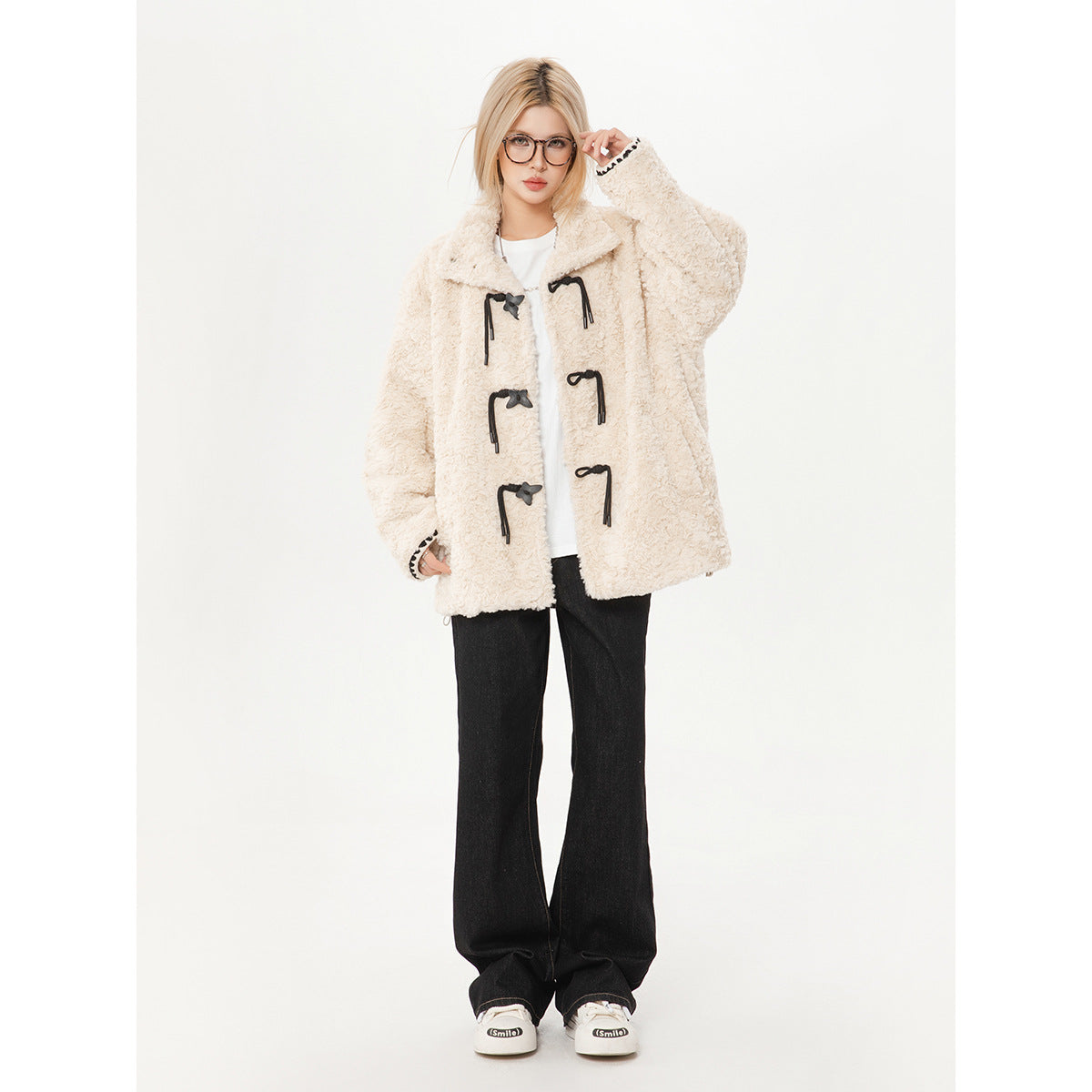 Full-length front view of a model wearing an ivory textured toggle coat, white top and black wide-leg pants.