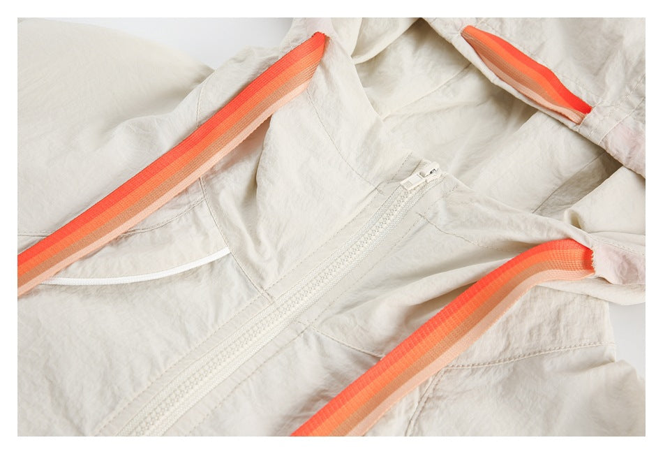 Cream jacket close-up showing a front zipper and orange-striped hood drawstrings.